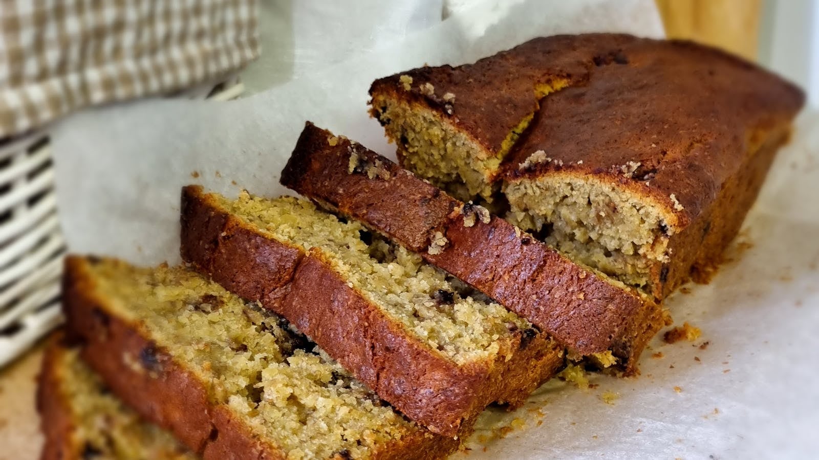 Banana bread / bolu pisang keemasan dipotong di atas kertas baking, tekstur lembab terlihat