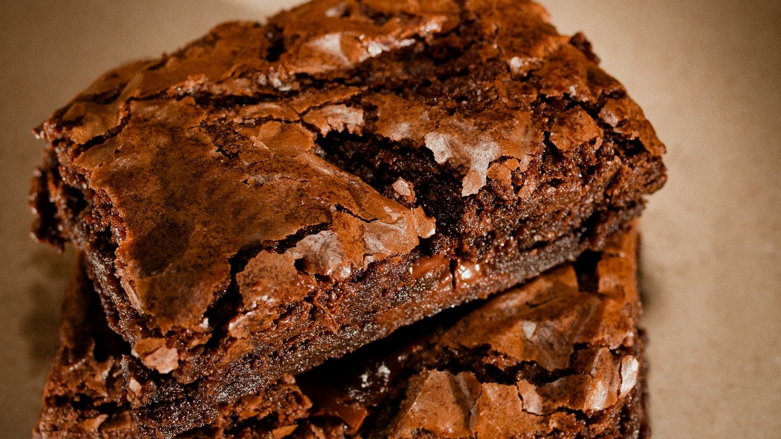 Tumpukan brownies cokelat fudgy dengan kerak mengkilap retak dan bagian dalam pekat lembab