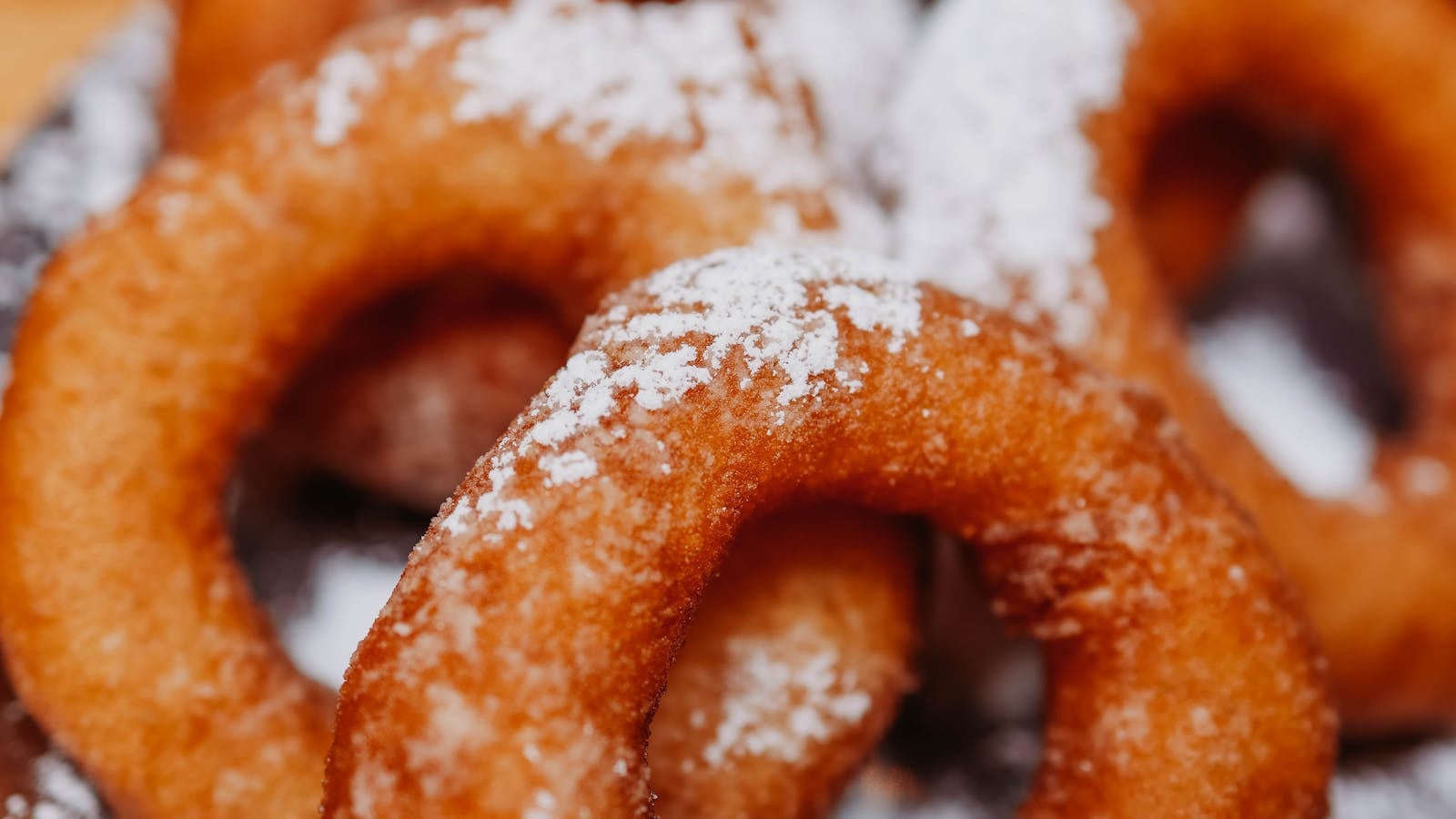 Tumpukan donat kentang bulat berlubang yang ditaburi gula halus
