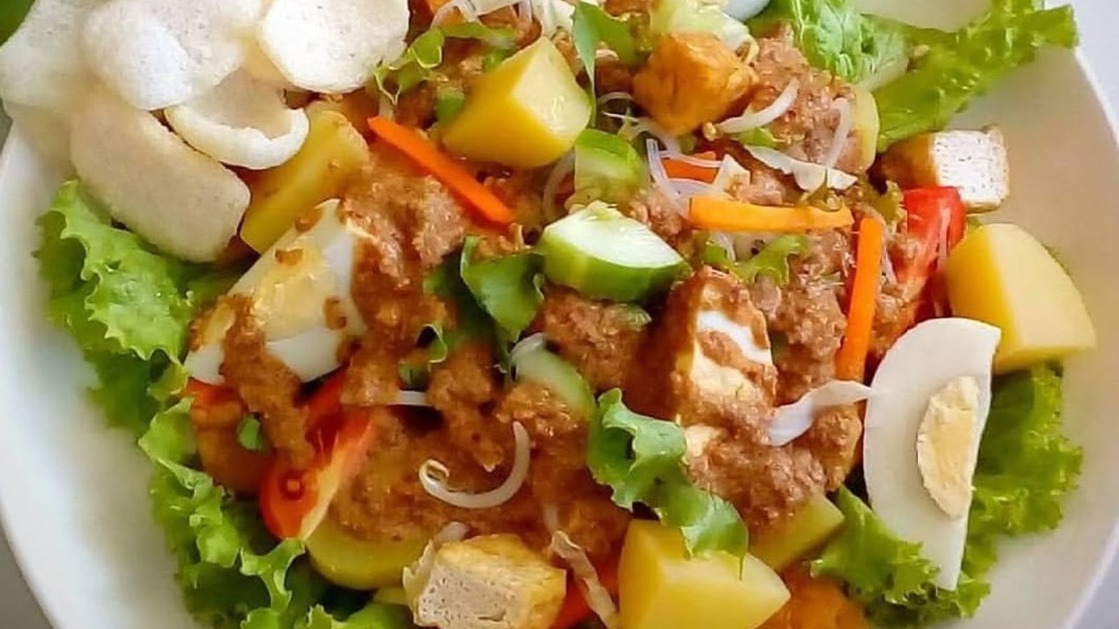 Gado-gado dengan sayur rebus, telur, lontong, dan siraman saus kacang
