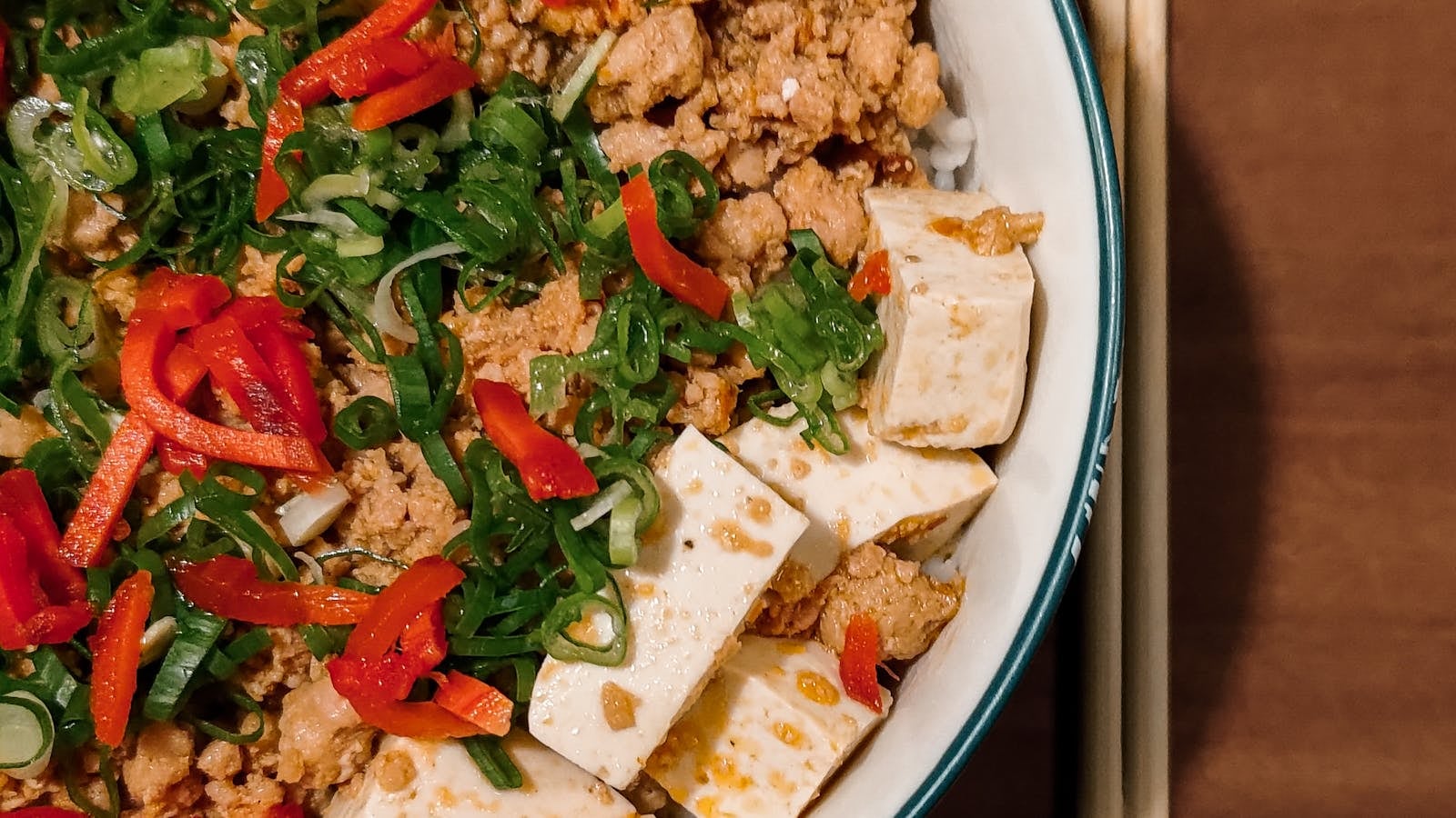 Mapo tofu Sichuan dengan tahu lembut dalam kuah merah pedas, taburan daun bawang dan lada sichuan