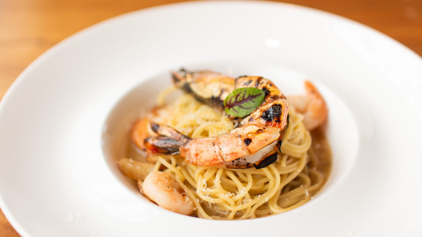 Pasta aglio olio dengan minyak zaitun dan peterseli di piring putih