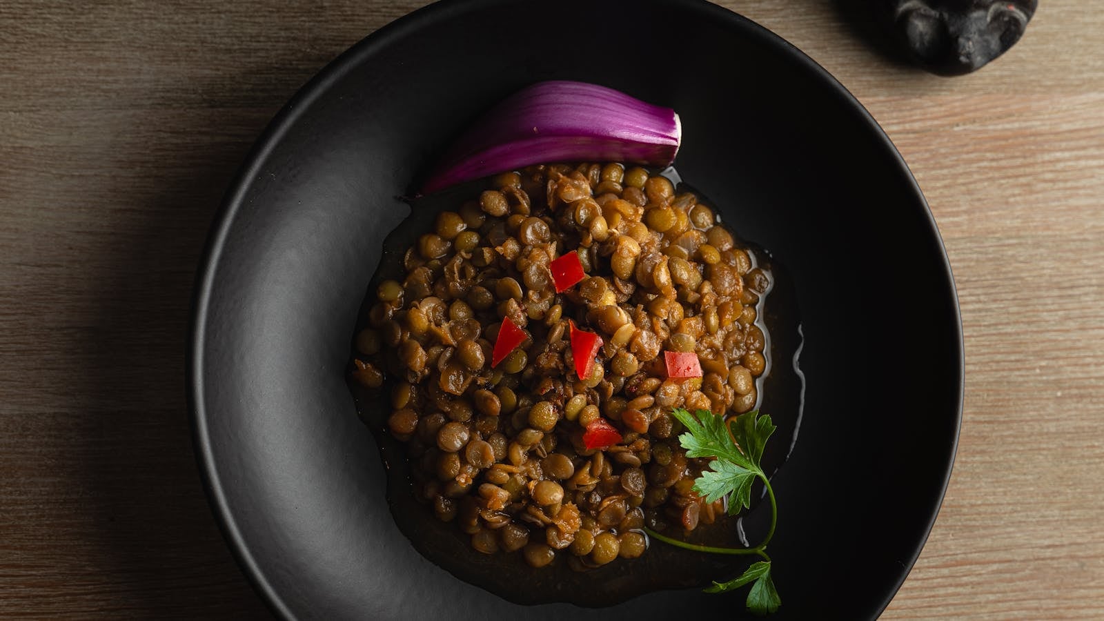 Mangkuk salad lentil hangat dengan peterseli segar dan irisan bawang merah ungu dari atas