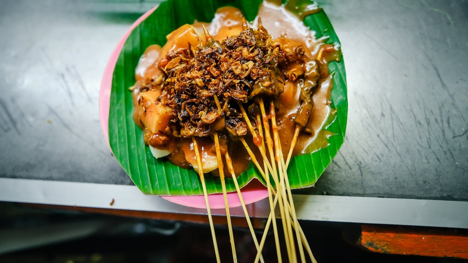 Sate Padang disajikan di atas daun pisang dengan kuah kuning